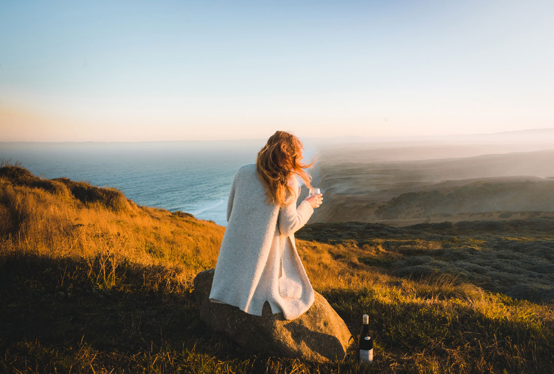 Woman drinking Sea Sun Chardonnay on coastal cliffs